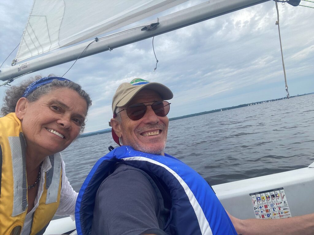A sailor with a disability and his companion sailor in a sailboat