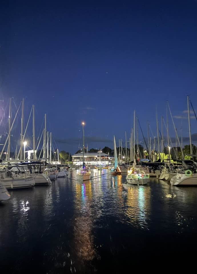 Boats illuminated with decorative lights motoring in the harbour.