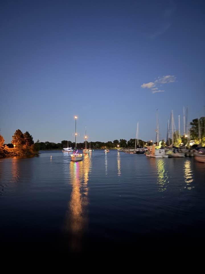 Boats illuminated with decorative lights motoring in the harbour.