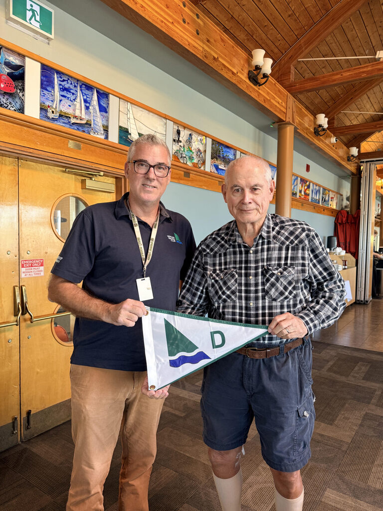 A man presenting a club burgee (pennant) to another man