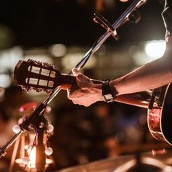 The arm of a man stretched to a guitar neck playing