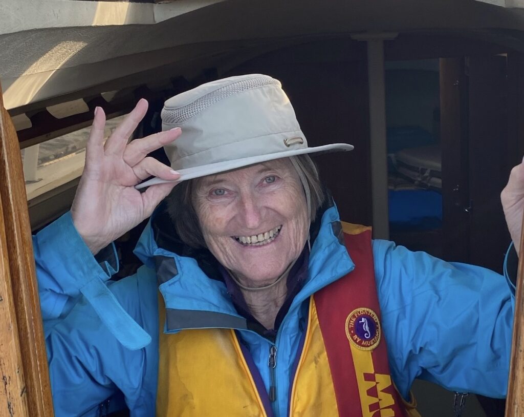 A smiling woman wearing a hat and life jacket.