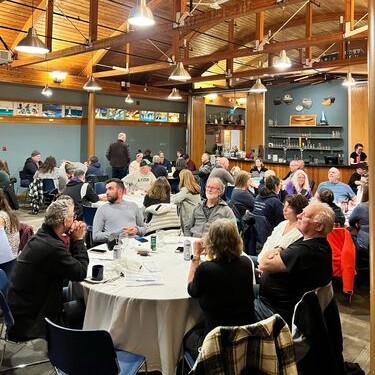 People seated around tables in a hall for Trivia Night