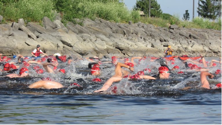Swimmers make their way through the water passing the breakwater