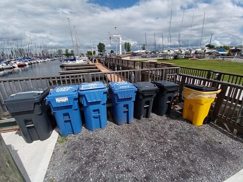 A row of garbage, recycle and hazardous waste bins.