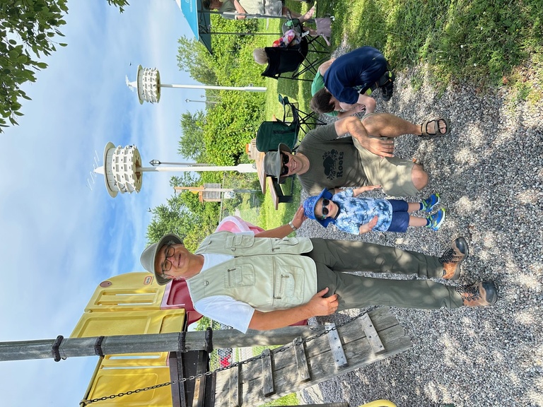 Several people standing with Purple Martin houses in background