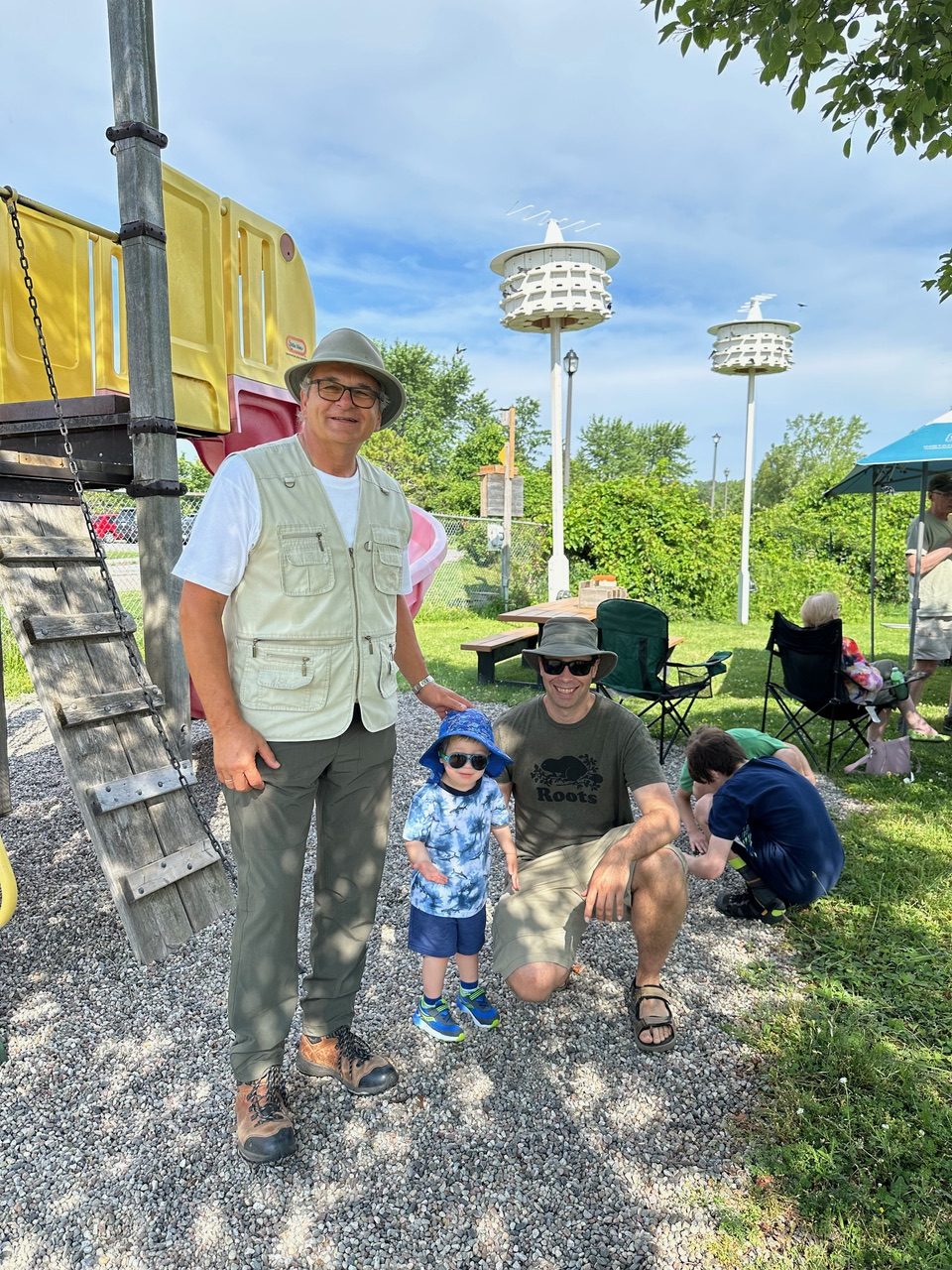 Several people standing with Purple Martin houses in background