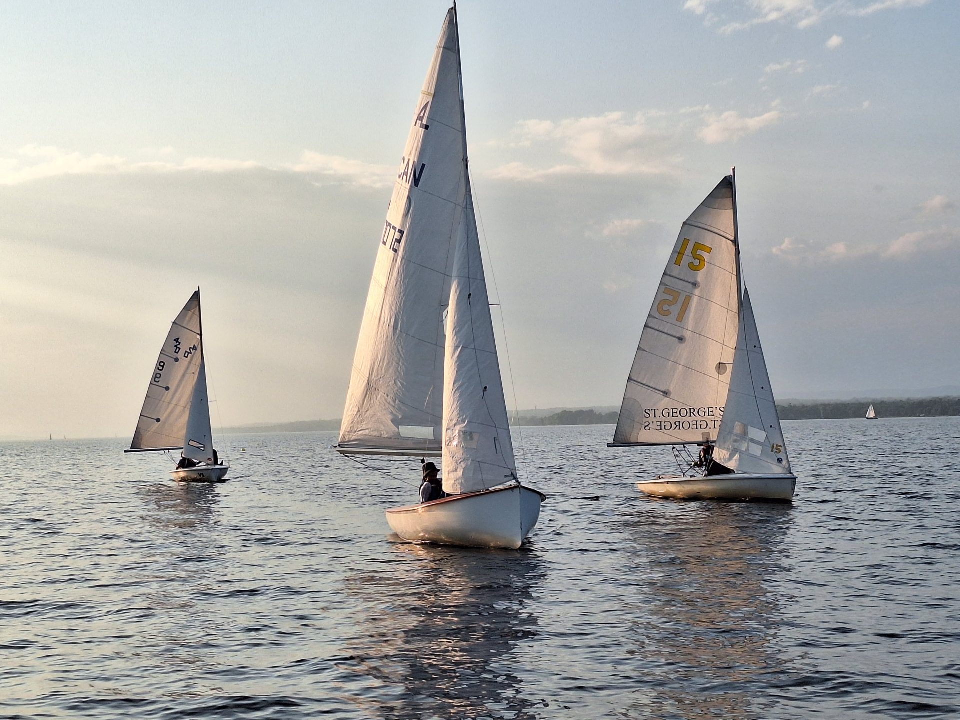Three dinghy sailboats sailing towards the photographer