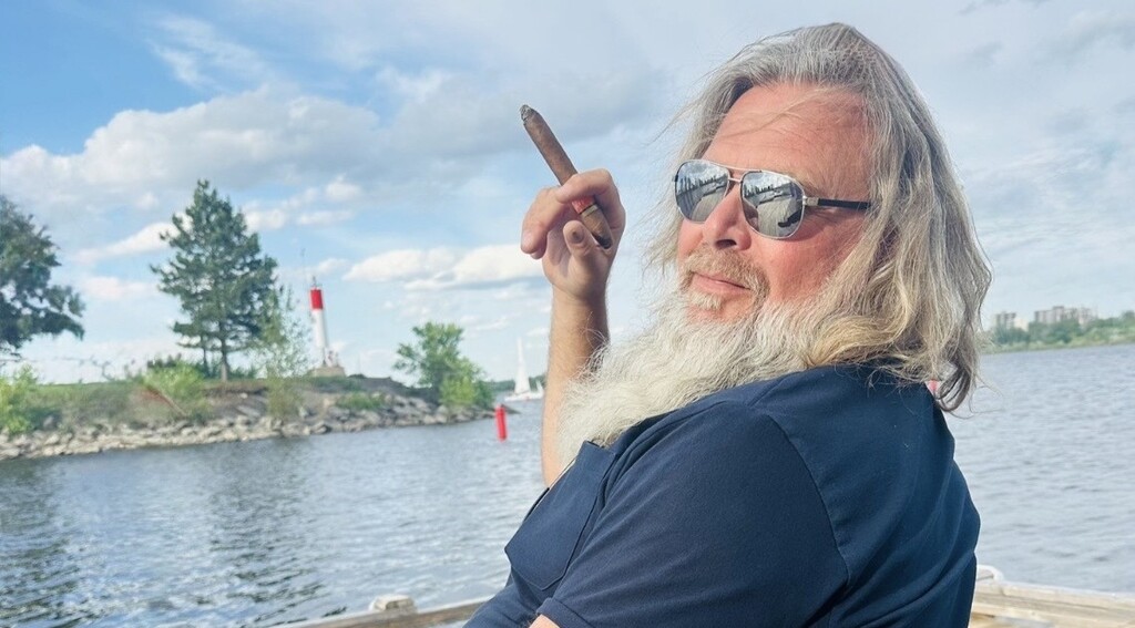 Doug Vandervelde sitting with a cigar overlooking the water and lighthouse