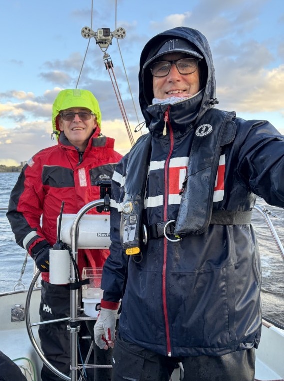 2 sailors near helm bundled up to keep warm