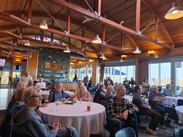 A crowd of people around tables in the club hall.